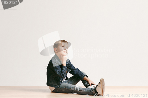 Image of The portrait of cute little boy in stylish jeans clothes looking at camera at studio