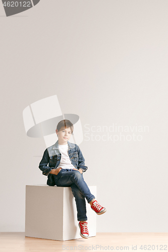 Image of The portrait of cute little boy in stylish jeans clothes looking at camera at studio