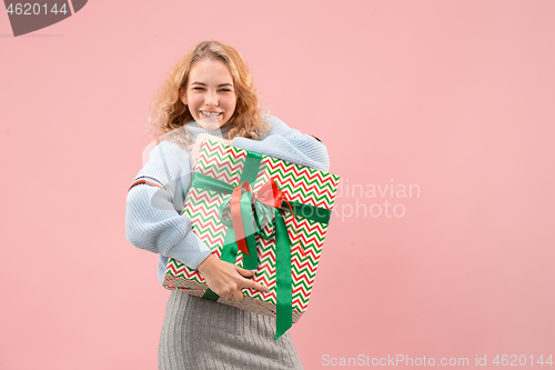 Image of Woman with big beautiful smile holding colorful gift box.