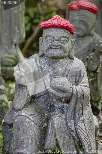 Image of Old stone statues of Buddhist monks and nuns wearing knitted and cloth hats
