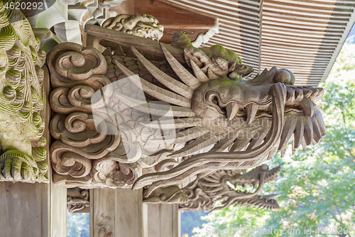 Image of Wooden carving of dragon decorates the gable of a roof over the entrance of an ancient Buddhist temple in Japan.