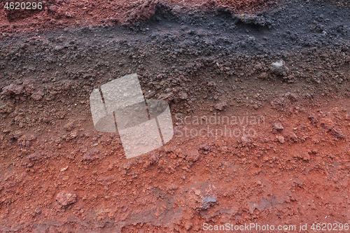 Image of A cut of soil with rocks and red soil