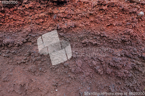 Image of A cut of soil with rocks and red soil