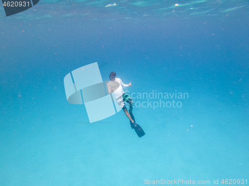 Image of Underwater view of man free diving in blue ocean.