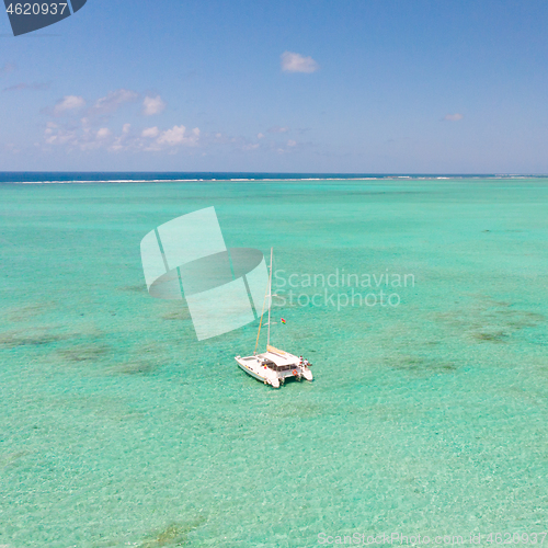 Image of Catamaran sailing boat in turquoise sea lagoon on tropial Mauritius island. Aerial, drone view.