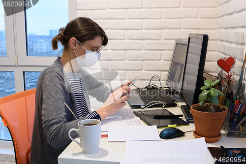 Image of A sick girl in a medical mask at home communicates on the phone