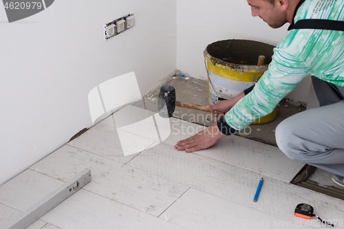 Image of worker installing the ceramic wood effect tiles on the floor