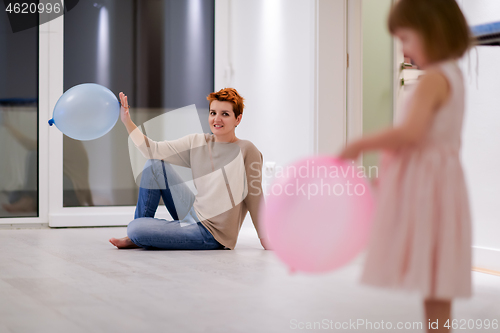 Image of mother and cute little daughter playing with balloons