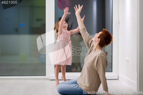 Image of mother and cute little daughter playing with balloons