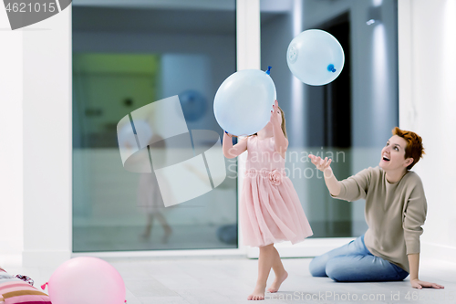 Image of mother and cute little daughter playing with balloons