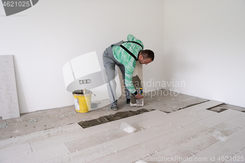 Image of worker installing the ceramic wood effect tiles on the floor