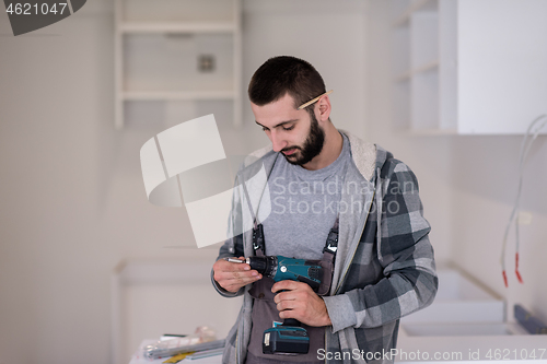 Image of the worker holding a hand drilling machine