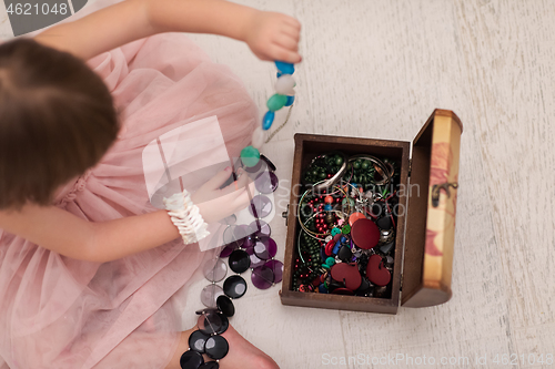 Image of little girl enjoying while playing with mother\'s jewelry