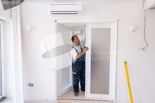 Image of carpenters installing glass door with a wooden frame