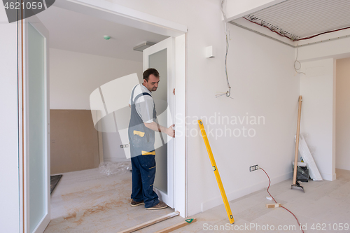 Image of carpenters installing glass door with a wooden frame