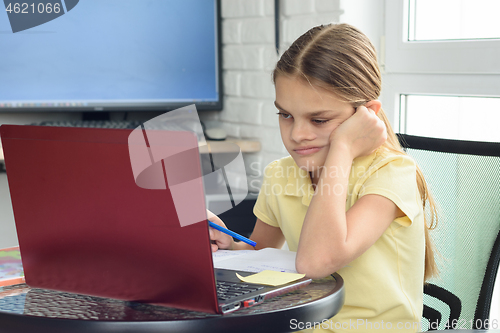 Image of Upset girl sitting in front of a laptop and doing homework