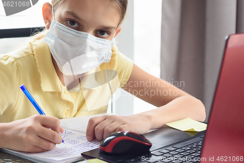 Image of The sick girl in self-isolation mode does her homework and looked into the frame.