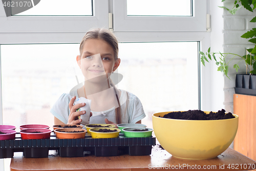 Image of Girl with bags of seeds and pots of earth sitting at the table