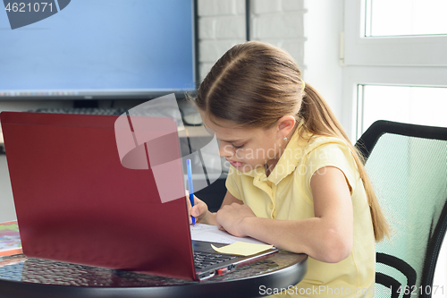 Image of Girl at home doing homework sitting in front of a laptop screen