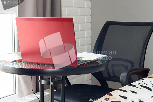 Image of A table on which there is a laptop and textbooks are laid out in the home interior
