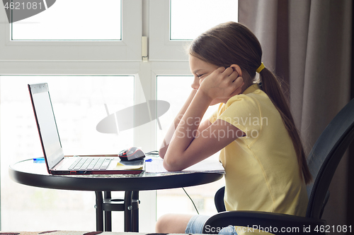 Image of girl sitting in front of a laptop and thinking about a solution to a problem