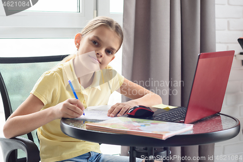 Image of The girl was distracted from the online lesson and looked into the frame