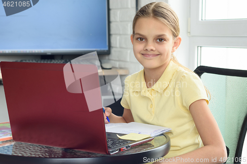 Image of Happy girl sitting in front of a laptop and studying remotely