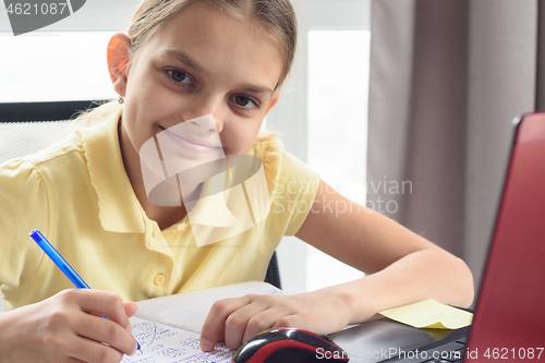 Image of Closeup portrait of happy girl doing homework in front of computer screen