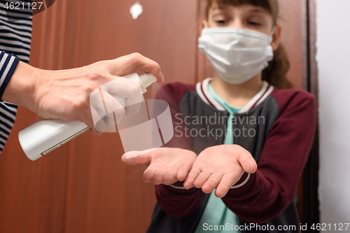 Image of After a walk on the street, the mother treats her hands with a disinfectant