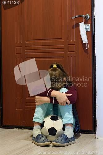 Image of Girl in quarantine period is tortured sitting with a ball at the front door