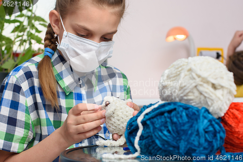Image of A sick girl in self-isolation is engaged in embroidery