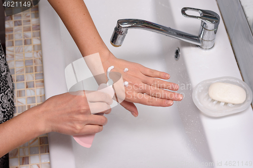 Image of The girl applied the cream to the skin of her hands in the form of an emoticon