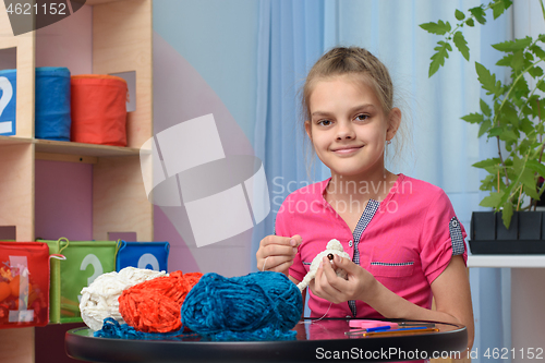 Image of The girl is engaged in embroidery of soft toys at home