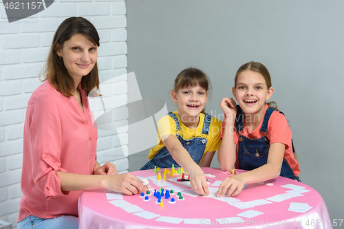 Image of Children and a young mother sit at a table and play a board game