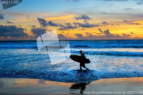 Image of Surfer with surfboard at sunset