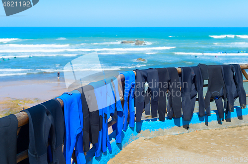 Image of Surfers wetsuits drying on beach