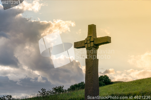 Image of a stone cross in front of a dramatic evening sky