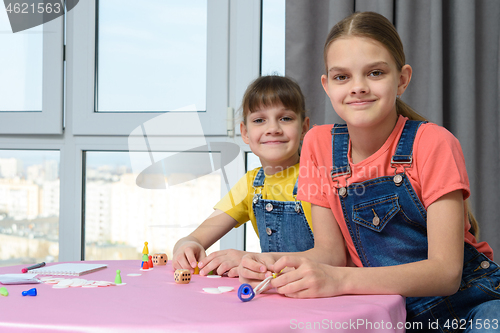 Image of Two girlfriends play board games for children and looked at the frame
