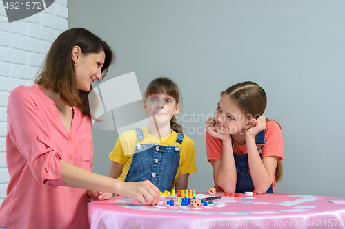 Image of Girl made a funny face playing board games with mom and sister