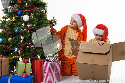 Image of Dona girl takes the ball from the Christmas tree, the other puts the toys in the box