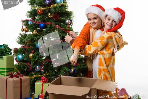 Image of Two girls funny take off toys from a New Year tree