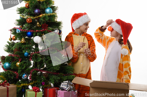 Image of A girl leaned a Christmas ball to her nose, another girl looks at her