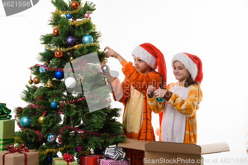 Image of Two girls decorate a Christmas tree isolated on white background