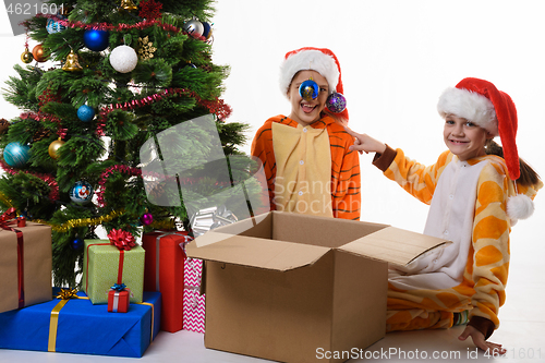 Image of The girl hung Christmas balls on her sister\'s hat and looked into the frame with a smile