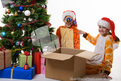 Image of The girl hung Christmas balls on her sister\'s hat and looked into the frame with a smile