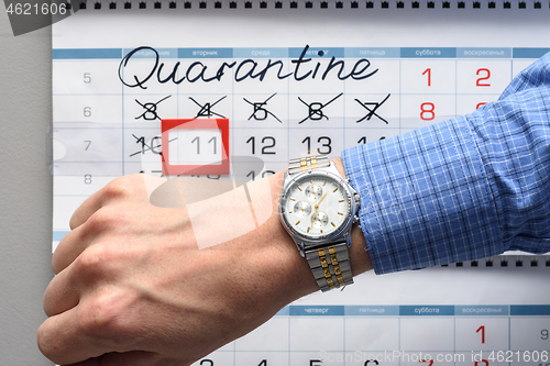 Image of The hand on which the watch is worn, in the background a calendar with the inscription Quarantine