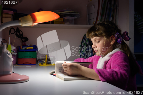Image of Girl at home doing homework under the light of a table lamp