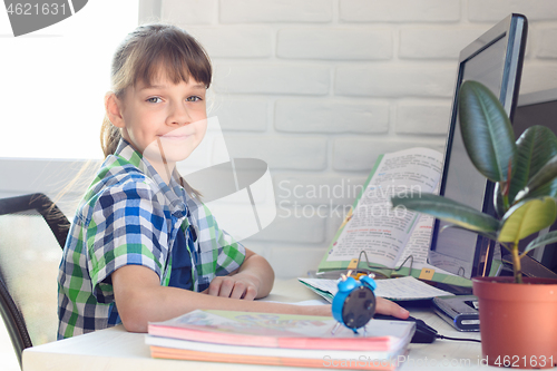 Image of The girl does homework at the table, looked into the frame