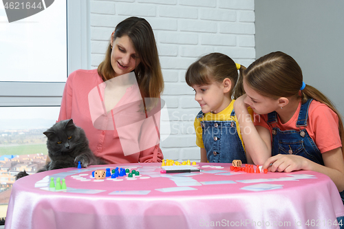 Image of The family watches as the cat plays a chip from the table from the board game