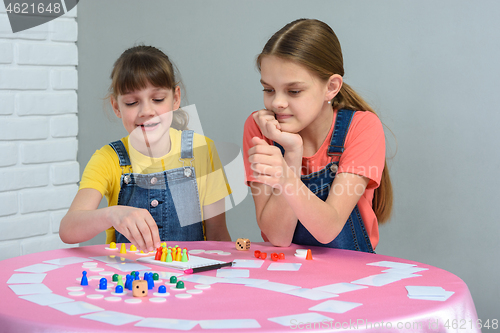 Image of Two girls at the table play a board game